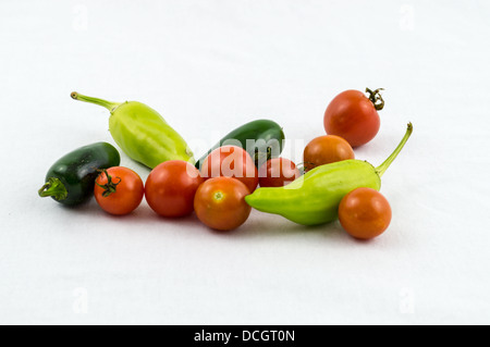 Assortiment de petits poivrons et tomates sur un fond blanc. Piments jalapeños et piments bananes, des produits fraîchement cueillis Banque D'Images