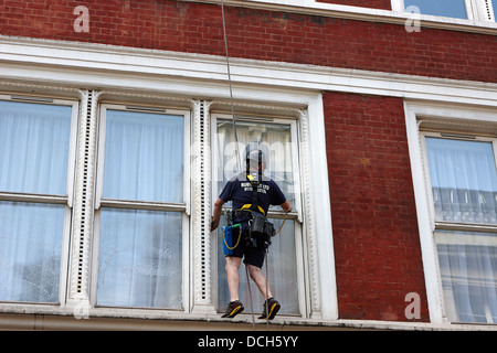 Nettoyant pour vitres à l'aide de la corde de rappel London England UK Banque D'Images