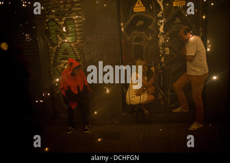 Barcelone, Espagne. Août 18, 2013. 18 août, 2013 - Barcelone, Espagne.Les téléspectateurs protégeant les charbons et prendre des photos.Correfocs, une vieille tradition catalane où les gens habillés en démons faire exploser des pétards et des fusées éclairantes, prendre part aux célébrations pour le Festival Sant Roc dans le quartier gothique de Barcelone. Crédit : Jordi Boixareu/Alamy Live News Banque D'Images