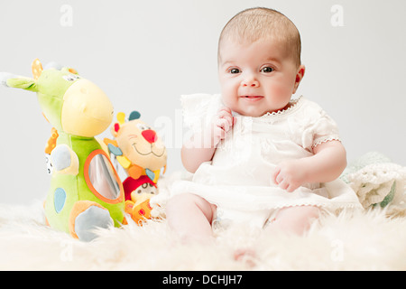 Bébé sur un tapis avec des jouets en peluche Banque D'Images