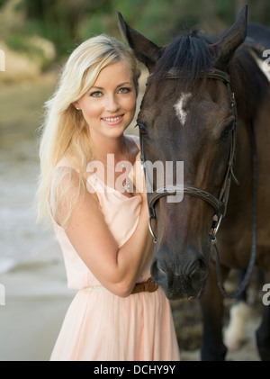 Belle blonde woman avec pur-sang hongre brun foncé / cheval sur la plage Banque D'Images