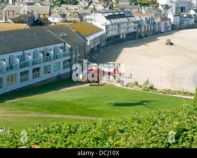 Cornwall Air Ambulance, décoller avec Porthmeor beach, St Ives en arrière-plan Banque D'Images