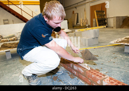 Blanc jeune apprenti bricklayer et platerer dans l'enseignement universitaire a métier qualifié Banque D'Images