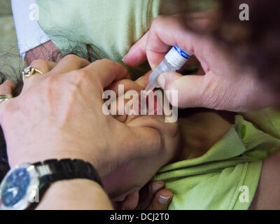 Jérusalem, Israël. Août 19, 2013. Un jeune enfant reçoit oralement deux gouttes de l'affaiblissement des souches de virus de la polio 1 et 3 dans un quartier d'une clinique de santé. Jérusalem, Israël. 19-août-2013. Israël lance une campagne nationale afin de stimuler l'inoculation de 1 millions d'enfants contre la poliomyélite, ayant trouvé le virus dans les eaux usées dans le sud. Bien qu'il n'y a eu aucun cas clinique de l'enfant virus, certains transporteurs ont été identifiés. Credit : Alon Nir/Alamy Live News Banque D'Images