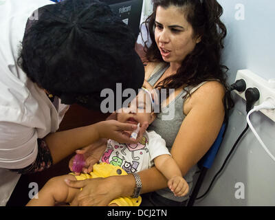 Jérusalem, Israël. Août 19, 2013. Un jeune enfant reçoit oralement deux gouttes de l'affaiblissement des souches de virus de la polio 1 et 3 dans un quartier d'une clinique de santé. Jérusalem, Israël. 19-août-2013. Israël lance une campagne nationale afin de stimuler l'inoculation de 1 millions d'enfants contre la poliomyélite, ayant trouvé le virus dans les eaux usées dans le sud. Bien qu'il n'y a eu aucun cas clinique de l'enfant virus, certains transporteurs ont été identifiés. Credit : Alon Nir/Alamy Live News Banque D'Images