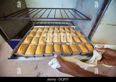 Femme tanzanienne dépose des petits pains d'un four de charbon à haute efficacité énergétique, en Tanzanie Banque D'Images