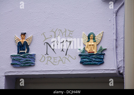 Lyme Dream non 17 Saillor et sirène avec des panneaux d'ailes au-dessus de la porte de la propriété aux murs pourpre à Lyme Regis, Dorset UK en août Banque D'Images