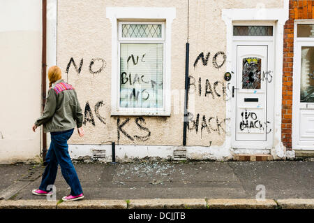 Belfast, en Irlande du Nord, Royaume-Uni. 19 août 2013 - Une femme regarde des graffitis racistes écrit sur les murs d'une maison récemment occupés par deux nigérians à Belfast. Crédit : Stephen Barnes/Alamy Live News Banque D'Images