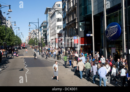 La foule des acheteurs, les travailleurs et les touristes passent le long d'Oxford Street sur un après-midi ensoleillé. Il y a une pause inhabituelle dans le trafic Banque D'Images