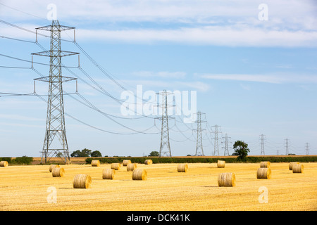 Les chaumes de blé dans un champ sur la côte est du Yorkshire, UK, avec des lignes haute tension à partir d'une centrale thermique au charbon. Banque D'Images