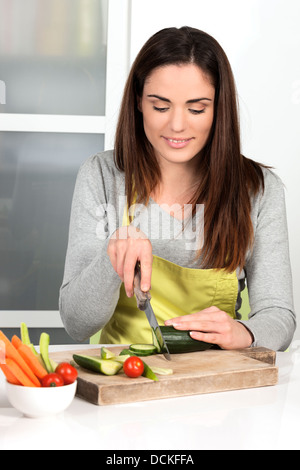 Belle femme concombre coupe et des légumes dans la cuisine Banque D'Images