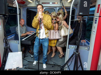 Hambourg, Allemagne. Août 19, 2013. Acteur de premier plan (Pfaff Luk avec microphone) et acteurs musicaux effectuer certaines parties de la nouvelle comédie musicale pendant un communiqué de date pour la nouvelle comédie musicale "ligne S1' dans un S-Bahn (réseau express régional) à Hambourg, Allemagne, 19 août 2013. L'Hamburg encore de fera la création à St Pauli Theatre le 08 septembre 2013. Photo : Georg Wendt/dpa/Alamy Live News Banque D'Images