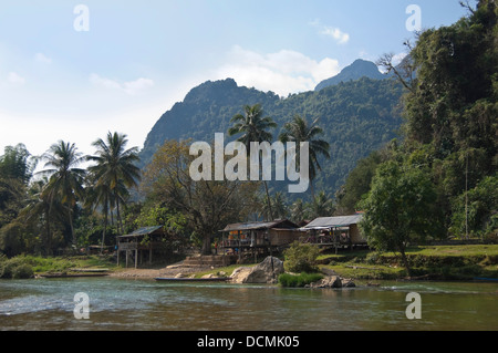 Vue horizontale de huttes en bois surélevée et des maisons le long des rives de la rivière Nam Song près de Vang Vieng Banque D'Images