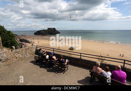 Tenby UK, lundi 19 août 2013 une mouette volant près de touristes sur un balcon donnant sur la plage du nord et St Catherine's Island à Tenby, Pembrokeshire. Re : le comportement agressif de mouettes à l'une des plus populaires stations balnéaires ont suscité des appels pour un "gull cull" - alors que l'on craint pour la sécurité publique. Les conseillers municipaux de Tenby dire goélands dans la ville sont en train d'attaquer les constructeurs sur les toits et les familles sur les plages. Le maire de la ville Sue Lane a demandé que l'autorité locale s'approcha pour voir si il y avait un moyen de contrôler les oiseaux belliqueux. Credit : D Legakis/Alamy Li Banque D'Images