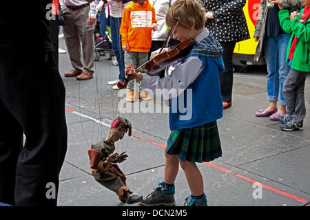 Édimbourg, Écosse, 20 août 2013, Colin McGlynn de Virginie aux États-Unis à l'âge de 7 ans pourrait être le plus jeune musicien ambulant sur le Royal Mile, au cours de l'Edinburgh Fringe Festival 2013. Il a diverti les passants en jouant des airs écossais sur son violon ainsi que la réalisation avec Mojo de JP Puppets Banque D'Images