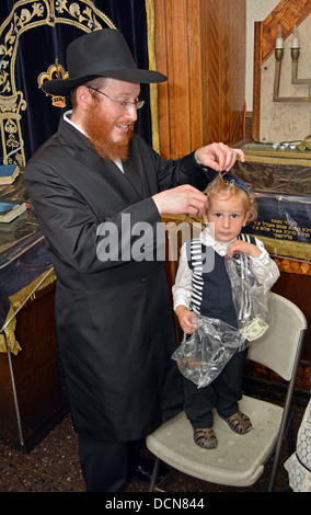 Un enfant de 3 ans garçon juif religieux obtenir sa première coupe de cheveux - Une serrure couper ici par son père - à un rituel appelé une Upsherinish Banque D'Images