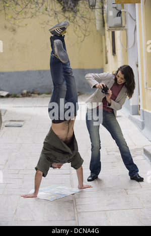 Woman photographing man doing handstand Banque D'Images