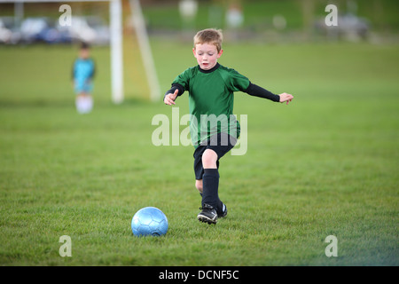 Young boy kicking soccer ball Banque D'Images