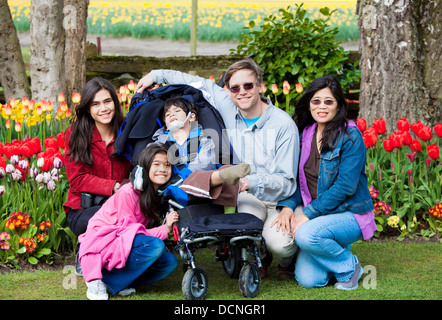 Famille avec mobilité boy dans les tulipes gardens Banque D'Images