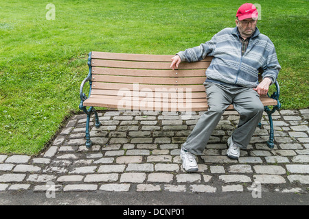 Un homme est assis, les Canadiens plus âgés à malheureux et perdu dans ses pensées, sur un banc de parc à King's Square, St John, Nova Scotia, Canada Banque D'Images