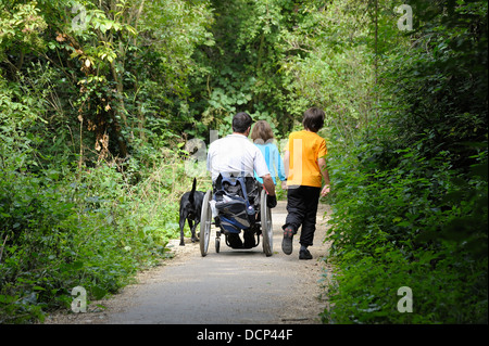 Un homme handicapé dans un fauteuil roulant avec ses enfants sur un sentier public England uk Banque D'Images