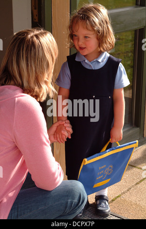 Mère rassurant sa fille le premier jour de son école, à l'extérieur du bâtiment de l'école Banque D'Images