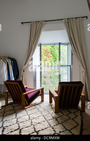 Des fauteuils et des habits à ouvrir les fenêtres de chambre à coucher Banque D'Images