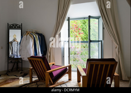 Des fauteuils et des habits à ouvrir les fenêtres de chambre à coucher Banque D'Images