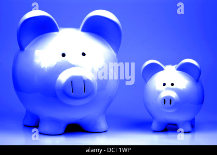 Deux white Piggy Banks debout sur fond bleu symbolisant l'épargne et de l'argent Banque D'Images