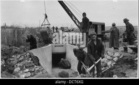 Cette image illustre les opérations de remblayage autour de structures en béton achevées aux camps BR-23 et 71-372 de CCC dans le cadre du projet Uncompahgre à Montrose, Colorado. La photo montre les travaux de construction en cours pendant l'ère du New Deal. Banque D'Images