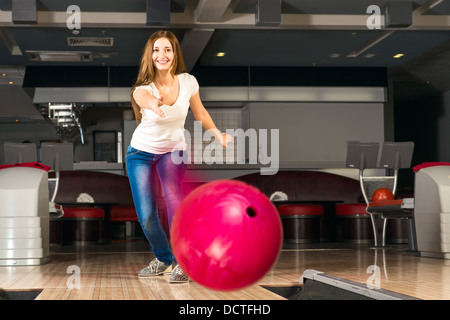 Agréable jeune femme jette une boule de bowling Banque D'Images