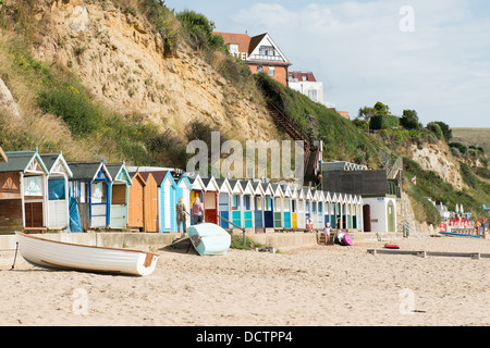 Cabines de plage en bois de couleur vive sur la plage de sable à Swanage dans le Dorset avec une falaise à l'arrière-plan. Banque D'Images