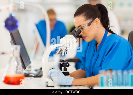 Belle jeune scientist using microscope in lab Banque D'Images