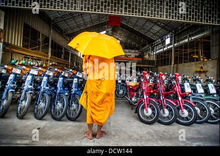 Le 4 janvier 2013 - Phnom Penh, Cambodge - Jan 4, 2013 - un moine bouddhiste est en attente de la nourriture à un shop de nouveaux cyclomoteurs dans la capitale cambodgienne de Phnom Penh ville...Histoire Résumé : Au milieu du rythme effréné de Phnom PenhÌ severnãƒ les rues de la ville, une véritable bête de transport pour les personnes et les marchandises qui émerge, vélos, motos, scooters, mobylettes, et motodups Tuk Tuks errent à la place des voitures et des camions. Près de 90  % des véhicules sur la capitale cambodgienne de près de 2,3 millions de personnes choisissent ces pour se déplacer. La congestion et l'environnement à la fois profiter de la petite taille et de petits moteurs. Busines Banque D'Images