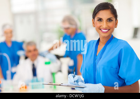 Cheerful young Indian chercheur médical rapport écrit dans le laboratoire Banque D'Images