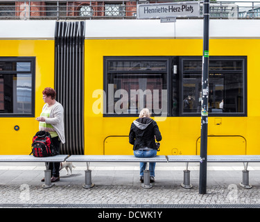 Tramway jaune et deux femmes en attente à un arrêt de tram à Berlin Banque D'Images