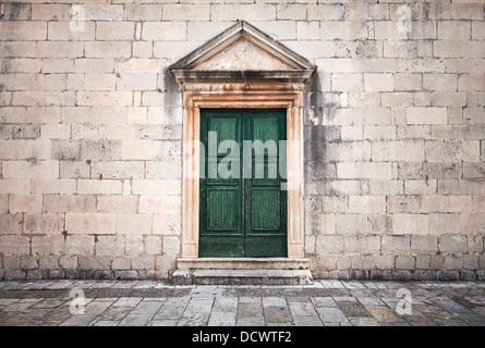 Mur en pierre avec porte en bois vert et pavés de vintage town square Banque D'Images