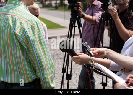 Un journaliste fait une interview avec un microphone Banque D'Images