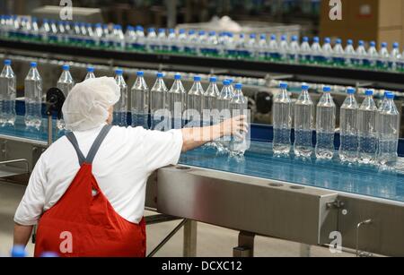 Un employé est photographié à côté de la ligne de production dans l'usine d'embouteillage de Coca-Cola Erfrischungsgetränke AG installation de production à Genshagen, Allemagne, 21 août 2013. Ici, Coca-Cola produits sont conditionnés dans un emballage jetable sur 158 000 mètres carrés. 170 employés travaillent dans l'installation de production, qui a été ouvert en 1998. Le Coca-Cola Erfrischungsgetränke AG est l'un des plus grands producteurs de boissons en Allemagne avec un volume de ventes de 3,7 milliards de litres en 2012. Photo : Jens Kalaene Banque D'Images