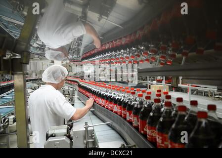 Un employé est photographié à côté de la ligne de production dans l'usine d'embouteillage de Coca-Cola Erfrischungsgetränke AG installation de production à Genshagen, Allemagne, 21 août 2013. Ici, Coca-Cola produits sont conditionnés dans un emballage jetable sur 158 000 mètres carrés. 170 employés travaillent dans l'installation de production, qui a été ouvert en 1998. Le Coca-Cola Erfrischungsgetränke AG est l'un des plus grands producteurs de boissons en Allemagne avec un volume de ventes de 3,7 milliards de litres en 2012. Photo : Jens Kalaene Banque D'Images