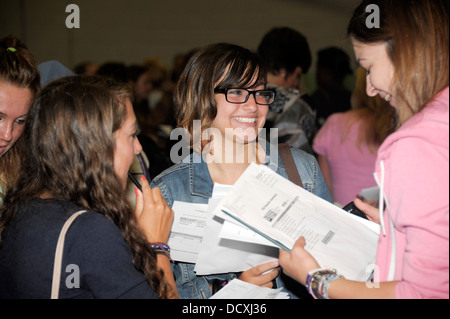 La réussite d'un femelle stuident GCSE avec son large sourire freinds après avoir reçu ses résultats d'examen. Banque D'Images