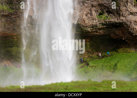 Les gens qui marchent derrière la cascade de Seljalandsfoss près de Hvolsvollur Islande Banque D'Images