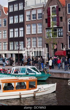 Les gens à bord des bateaux de croisière et des maisons historiques par le canal à Amsterdam, Pays-Bas. Banque D'Images