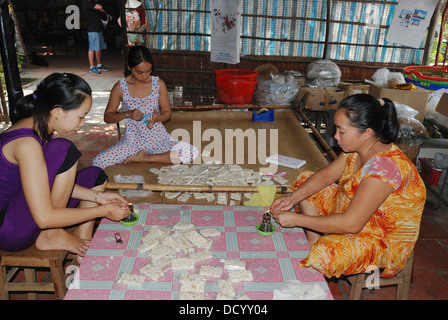 Les femmes rétractable gâteaux de riz vietnamiens dans une entreprise familiale. À Cai Be, Delta du Mekong, Vietnam. Banque D'Images