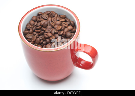 Mug rouge avec des grains de café dans un livre blanc sur ce fond isolé. Banque D'Images