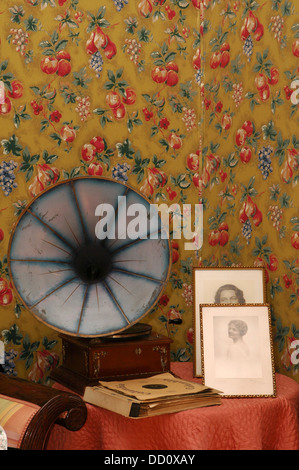 Ancien gramophone à manivelle portable haut-parleur dans la salle de séjour avec une décoration papier peint floral Banque D'Images