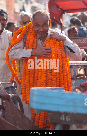 Un vendeur de fleurs de souci porte guirlandes autour du cou à la Chandni Chowk marché aux fleurs dans la vieille ville de Delhi, Inde. Banque D'Images