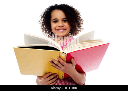 Smiling cute school girl reading a book, se préparer en vue des examens. Banque D'Images