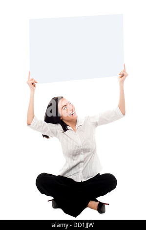 Jolie femme assise sur le sol et la tenue de tableau blanc au-dessus de sa tête. Banque D'Images