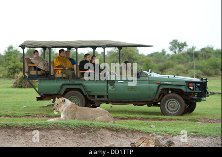 Les touristes dans un véhicule de safari regarder un lion (Leo) Panthero, Madikwe Game Reserve, Afrique du Sud Banque D'Images